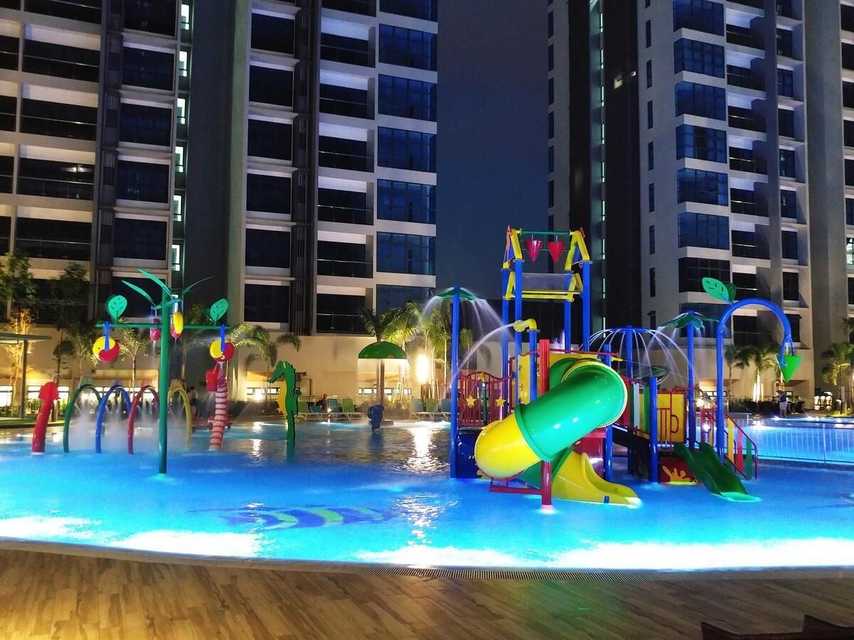 Zona de parque acuático con toboganes y estructuras de juego, rodeada de edificios altos.
