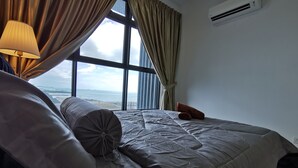 A hotel room with a large bed, a view of the sea, and an air conditioning unit on the wall. - Thermospace Management (Malacca City)