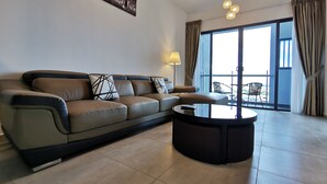 A modern living room with a leather sofa, a round coffee table, a ceiling fan, and a large window with curtains. - Thermospace Management (Malacca City)
