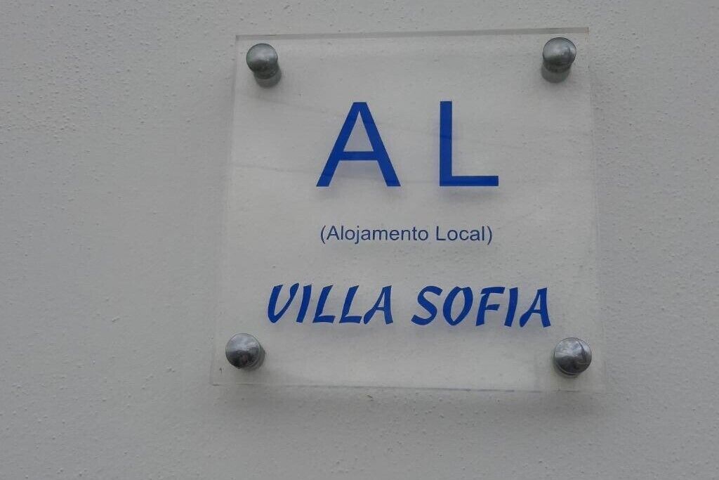 Valkoisella seinällä on kyltti, jossa lukee: ”AL (Alojamento Local) VILLA SOFIA”.