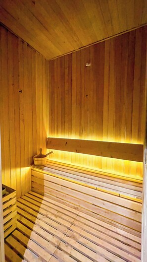 Relax in a serene sauna room with a sloped ceiling and wooden bench along the wall.