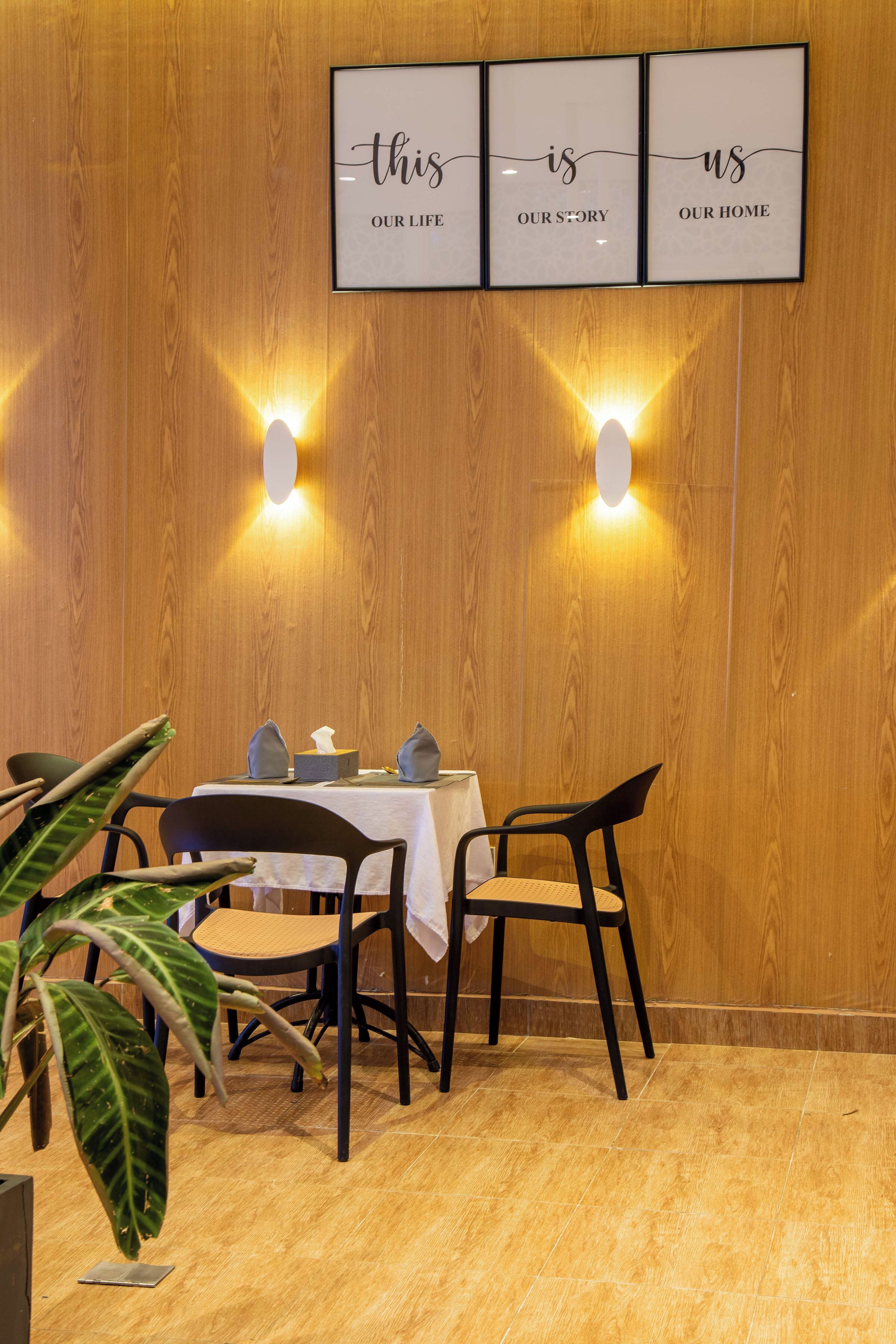 Un espace repas avec un mur en bois, une table entourée de chaises et un panneau encadré au-dessus.