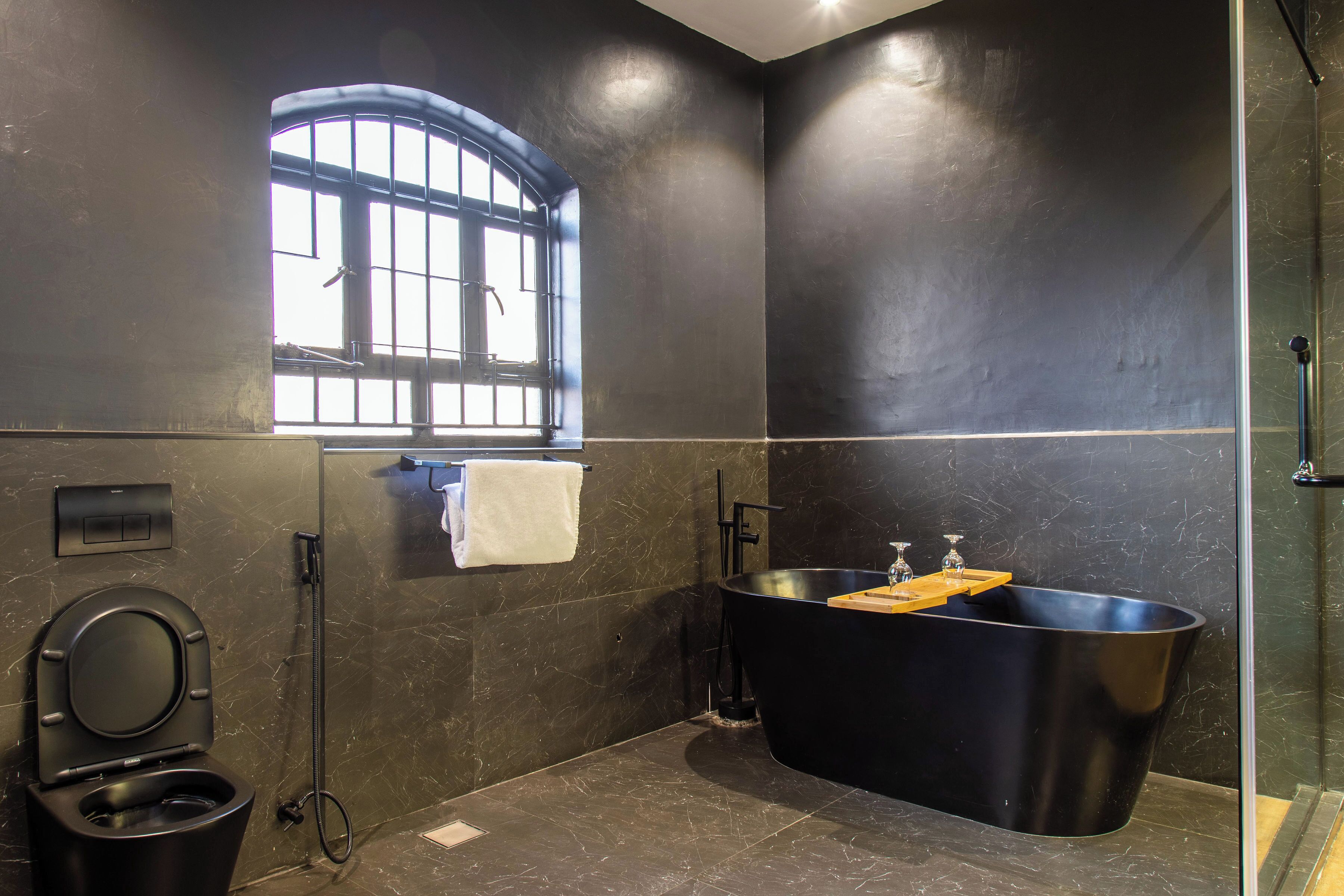 A modern bathroom with a toilet, a bathtub, and a window.