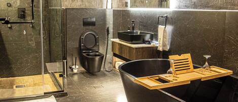 A modern bathroom with a glass-enclosed shower, a freestanding bathtub, a vanity with a sink, and a mirror above the vanity.