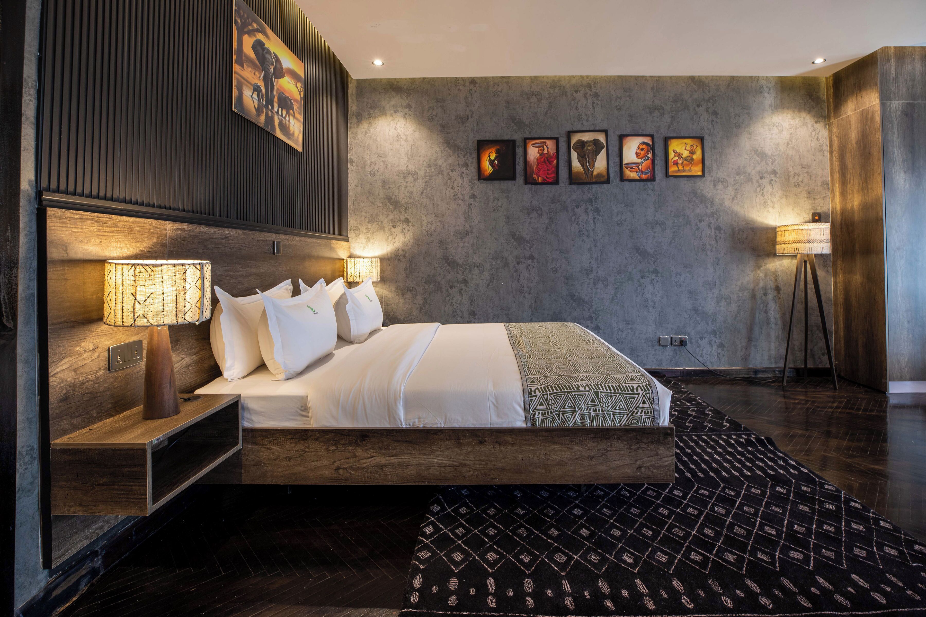 A modern hotel room with a large bed, bedside lamps, a wooden headboard, and a patterned rug.
