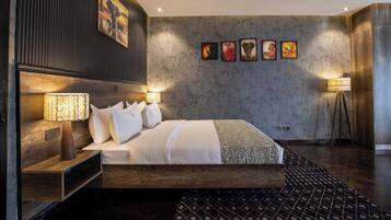 A modern hotel room with a large bed, bedside lamps, a wooden headboard, and a patterned rug.