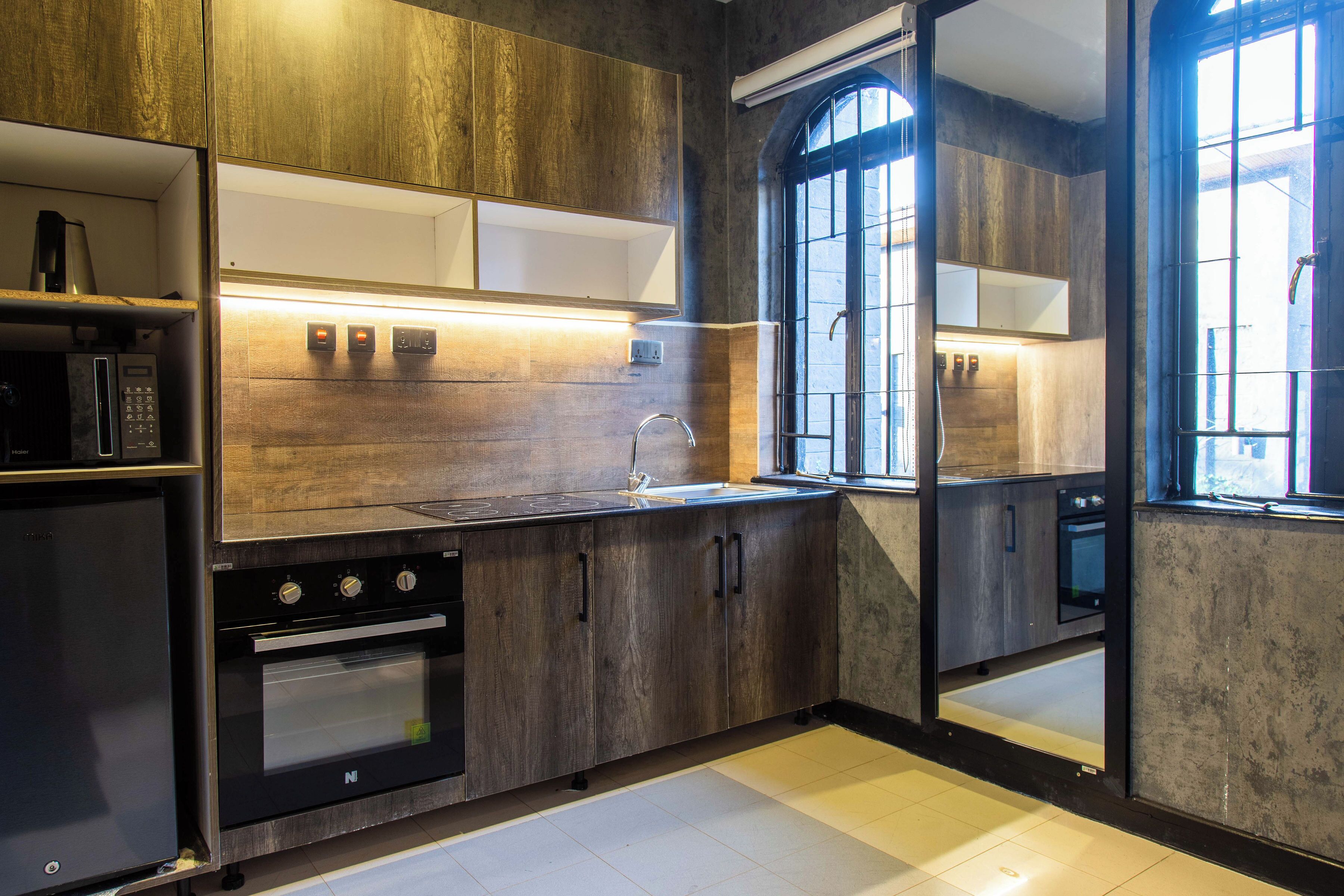 Una cocina moderna con armarios de madera, horno empotrado y ventana con vistas.