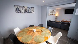 A dining area with a round wooden table, white chairs, and a painting on the wall. - Résidence Hermès Paris Orly Aéroport (Villeneuve-le-Roi)