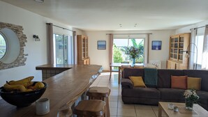 A spacious living area with a wooden dining table, a sofa with cushions, and a coffee table with a vase. - 4 bedroom villa with swimming pool, in a large lush garden, 3km from the beaches (Messanges)