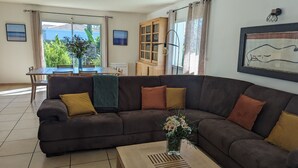 A living room with a brown sofa, a wooden coffee table, and a vase of flowers. - 4 bedroom villa with swimming pool, in a large lush garden, 3km from the beaches (Messanges)