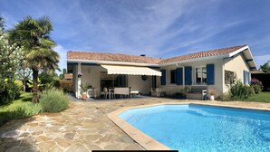 A house with a swimming pool, a covered patio, and a garden with palm trees. - 4 bedroom villa with swimming pool, in a large lush garden, 3km from the beaches (Messanges)