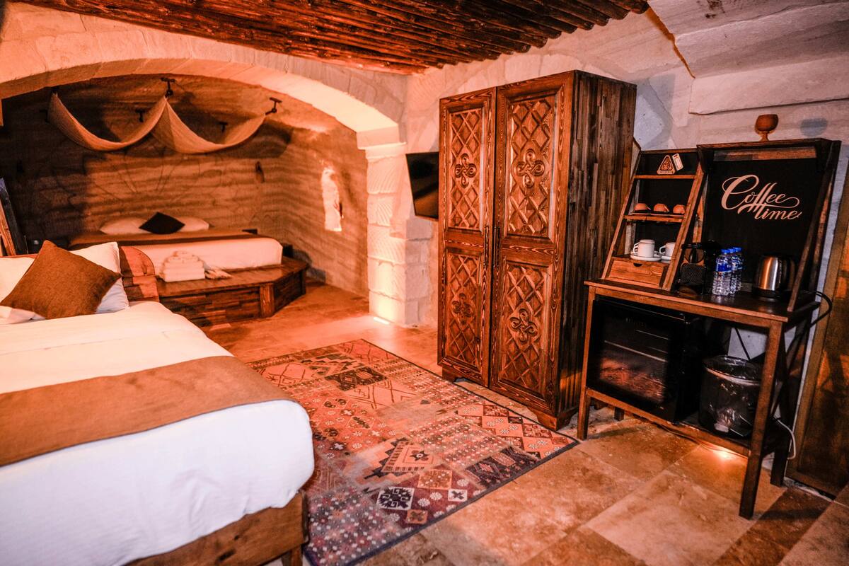 Una habitació acollidora amb un llit, un armari de fusta, un espai per al cafè i una catifa amb dibuixos.