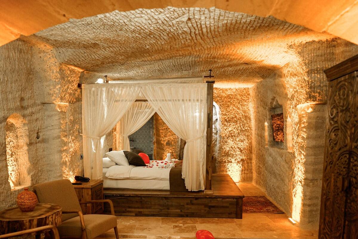 Un dormitori acollidor amb un llit amb cortines, una zona de seients amb cadires i una catifa decorativa.