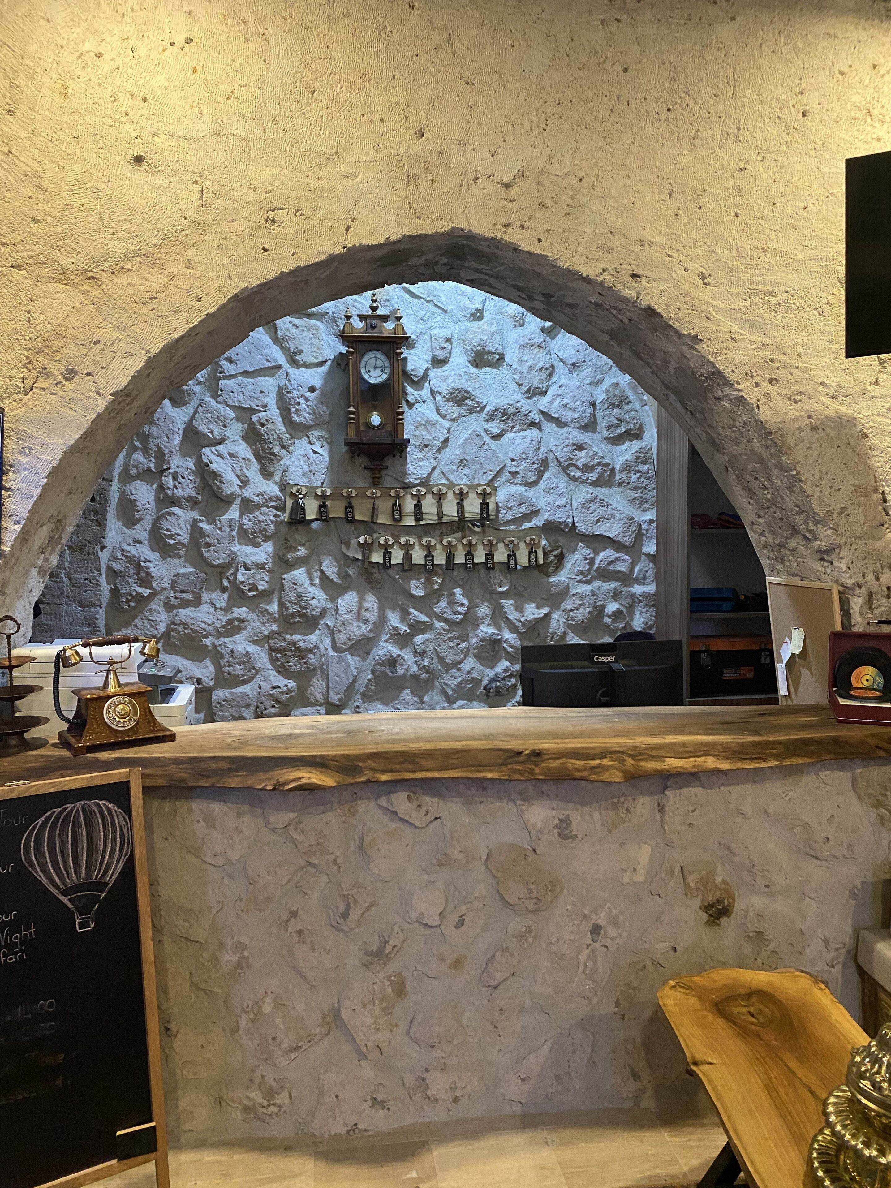 A stone wall with a clock and a coat rack.