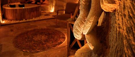 An interior with a stone sculpture, a fireplace, and a round rug.