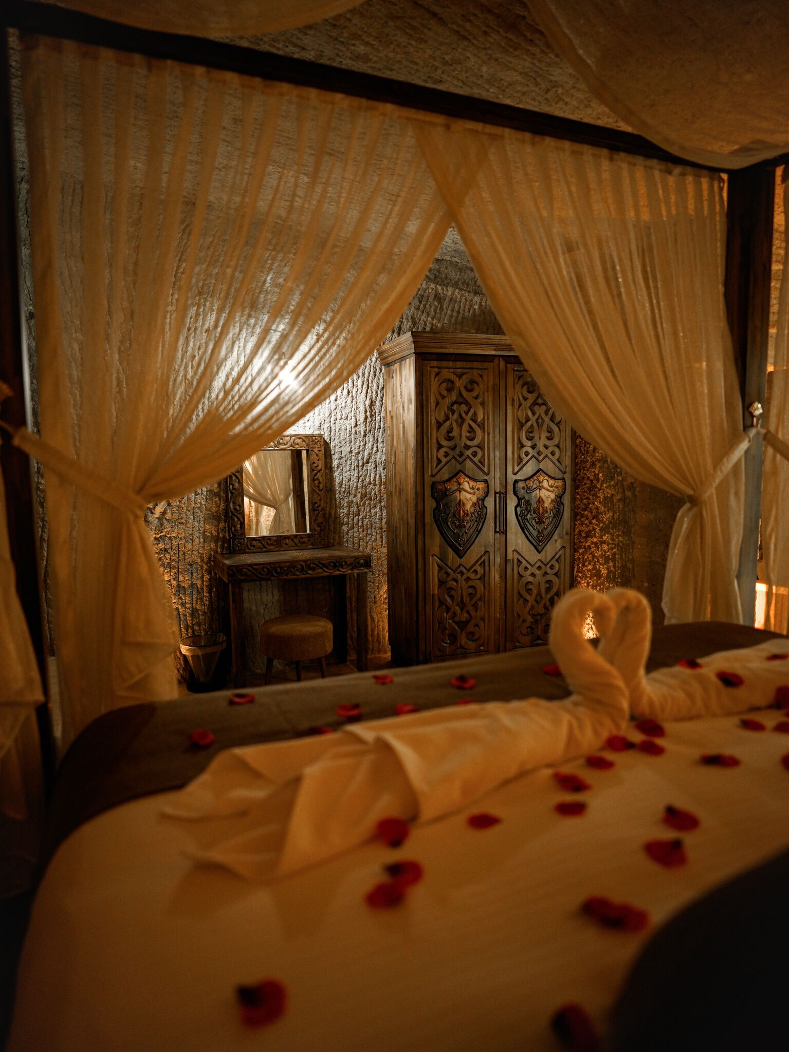 A room with a bed, a wooden cabinet, and a mirror.
