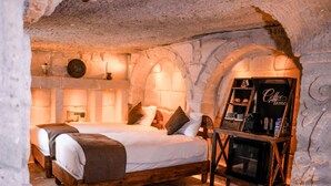 Quarto acolhedor com paredes de pedra, uma cama, um espaço para café e uma lareira.
