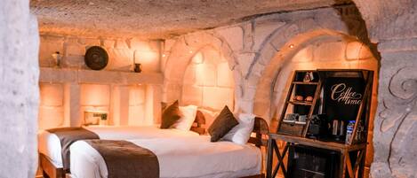 A cozy, stone-walled bedroom with a bed, a coffee station, and a fireplace.