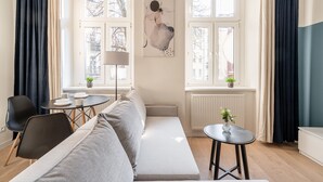 Ein modernes Wohnzimmer mit einer Couch, einem Esstisch und zwei mit Vorhängen versehenen Fenstern.
