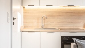 Eine moderne Küche mit weißen Schränken, einer Holz Arbeitsplatte, einer Spüle und einem Geschirrspüler.