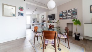 A modern dining area with a glass table, wooden chairs, and a central vase. - The Nine Elms Collection (London)