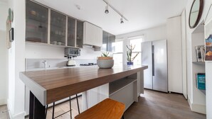 A modern kitchen with a wooden countertop, a built-in stove, and a refrigerator. - The Nine Elms Collection (London)