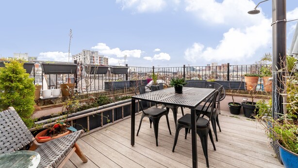 A rooftop terrace with a table and chairs, potted plants, and a view of the cityscape. - The Nine Elms Collection (London)