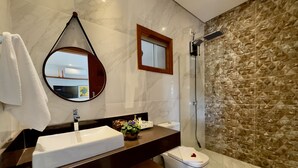 A modern bathroom with a marble vanity, a round mirror, a shower with a textured wall, and a toilet. - Loft Rua Direita Você vai Adorar Este Lugar Único e Romântico (Centro Pirenópolis)
