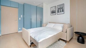 Ein modernes Schlafzimmer mit einem Bett, einer Couch und einem Kleiderschrank.
