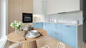 Eine moderne Küche mit hellblauen Schränken, einem Holztisch und einer weißen Fliesenspiegel.