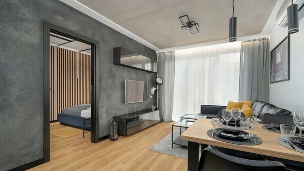 A modern living room with a dining area, a sofa, a TV, and a large window with curtains. - Stylish Apartment | Balcony (Poznan)