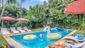A pool area with lounge chairs, inflatable toys, and a fruit basket.