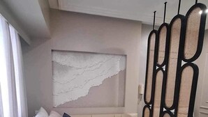 A modern bedroom with a large bed, a decorative wall piece, and a unique black and beige headboard. - The Hamptons - a luxury Cebu Condo near Ayala (Cebu City)