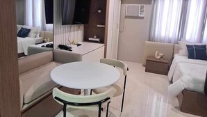 A modern hotel room with a dining area, a sofa, a TV, and a bed. - The Hamptons - a luxury Cebu Condo near Ayala (Cebu City)
