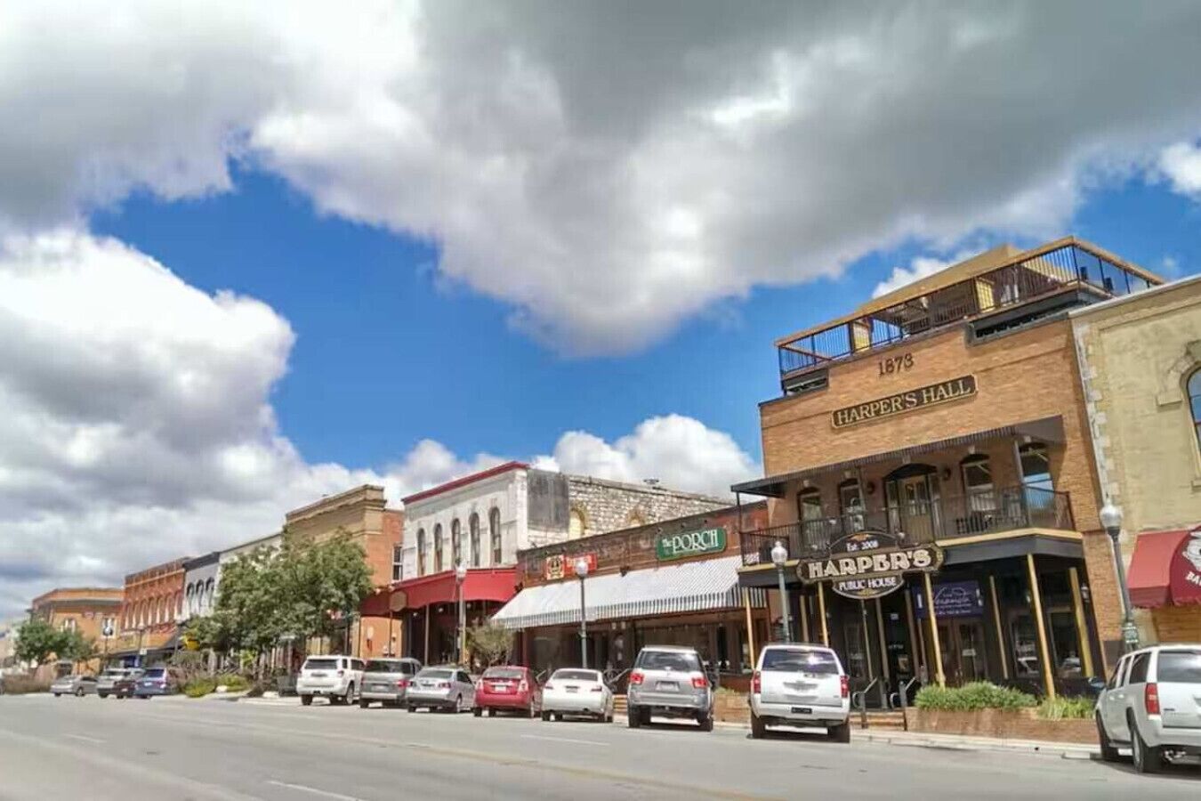 A street view with buildings, including a hotel named 'Harpers Hall' with a balcony and a sign indicating 'Est. 2008'.