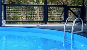 A clear blue swimming pool with a metal ladder and a safety fence.