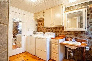 A compact kitchen with a washing machine, a stove, and a sink.