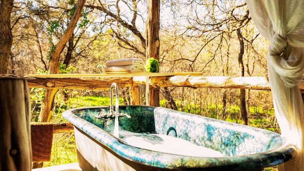 An outdoor wooden deck with a vintage bathtub. - Rustic Retreat: Tub, Firepit, Porch Swings & Pool (San Marcos)