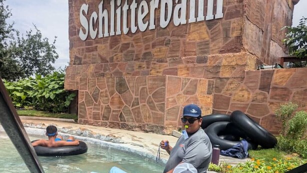 A water park with a stone wall labeled 'Schlitterbahn' and people floating on water tubes. - Outpost Vibes: Outhouse, Outdoor Shower & Pool (San Marcos)