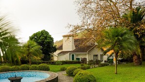 Una casa con piscina, rodeada de césped cuidado y palmeras.