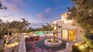 A modern outdoor patio with a pool, stone pathways, and a dining area. - BRAND NEW, SECLUDED VILLA WITH PRIVATE POOL AND AMAZING VIEW, CLOSE TO THE TOWN. (Rethimno)