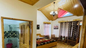 A bedroom with a wooden ceiling, a bed, a desk, and a bathroom with a shower and toilet. - Hotel Jamla Regency Manali (Manali)