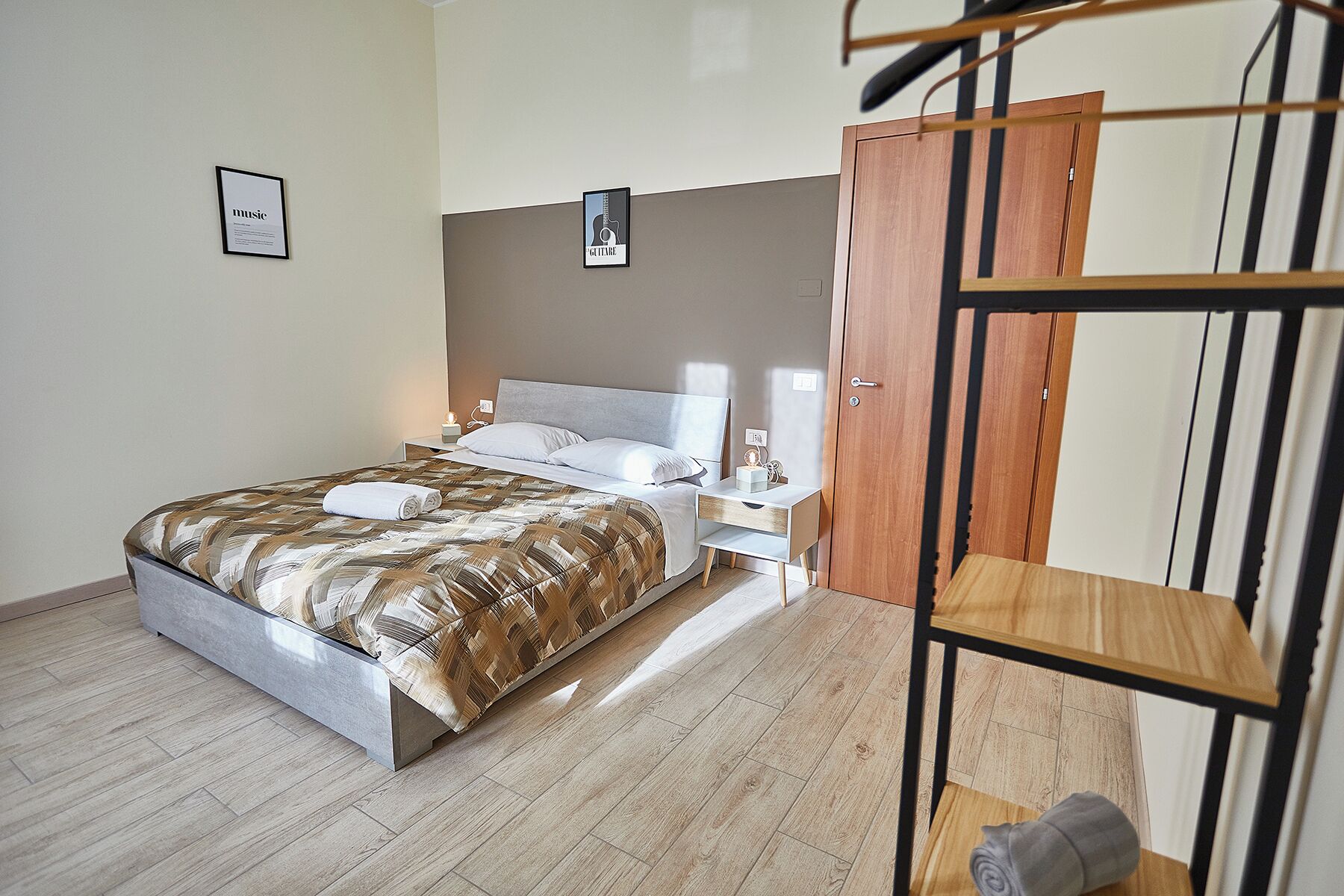 Een slaapkamer met een bed, nachtkastje, lamp en een houten kledingkast.