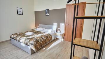 Een slaapkamer met een bed, nachtkastje, lamp en een houten kledingkast.