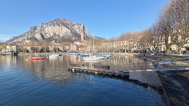 Un port de plaisance avec des bateaux amarrés, un quai et une montagne en arrière-plan.