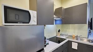 Une cuisine moderne dotée d’un four à micro-ondes encastré, d’appareils électroménagers en acier inoxydable et d’un aménagement compact.