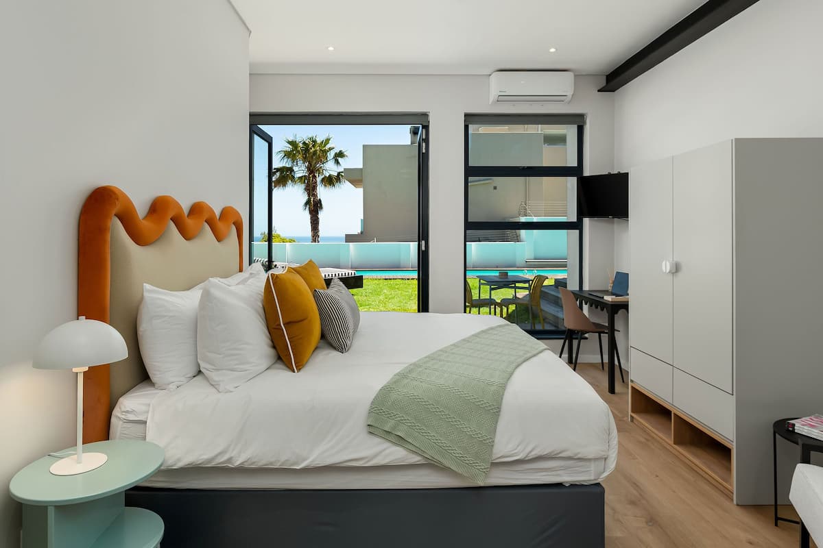 Une chambre moderne avec un grand lit, un bureau et une vue sur l’extérieur.