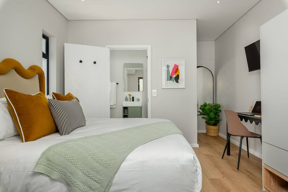 Une chambre à coucher moderne avec un grand lit, un bureau et une plante en pot.