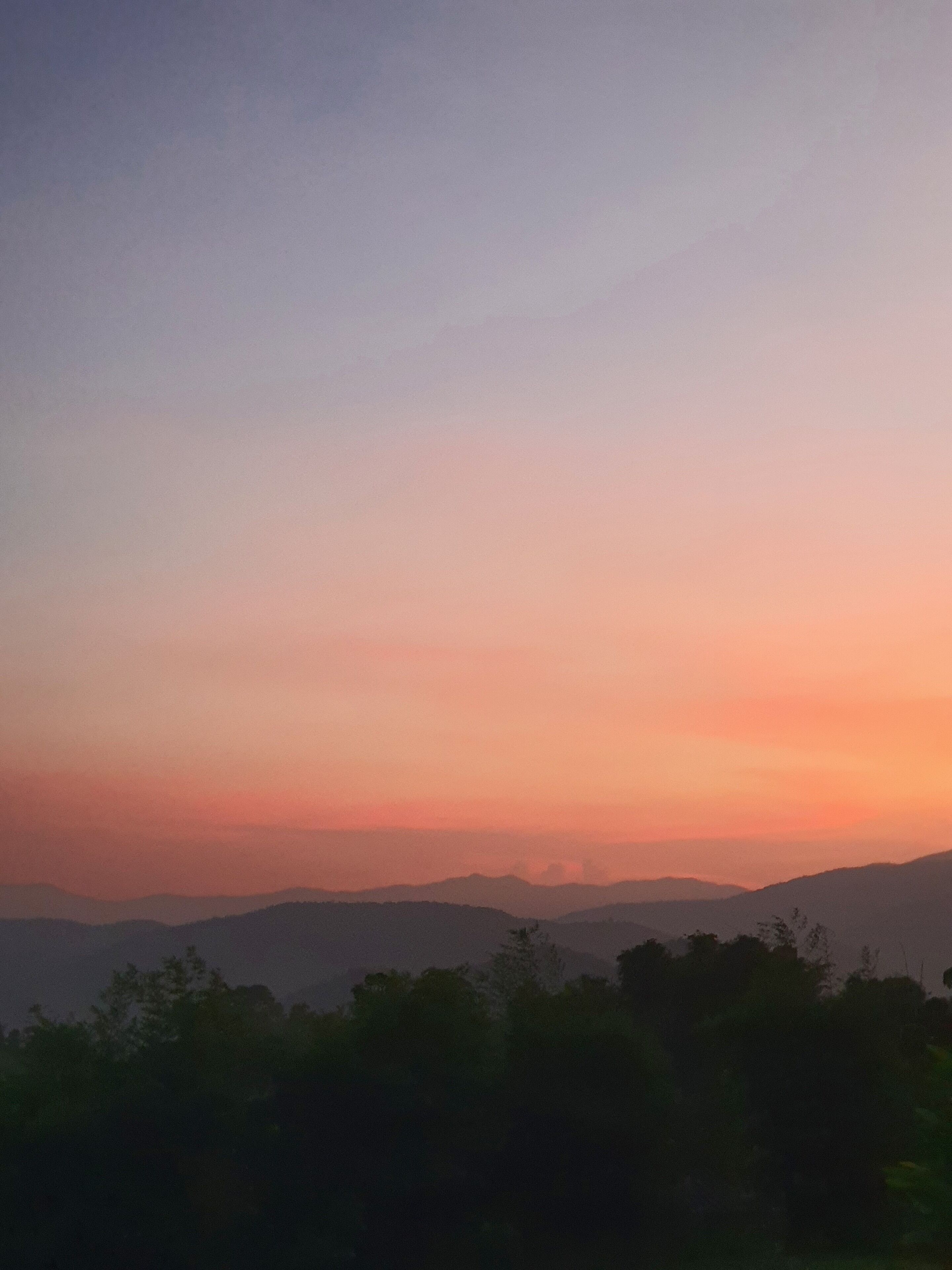 A landscape view of a mountainous area with a clear sky during sunset.