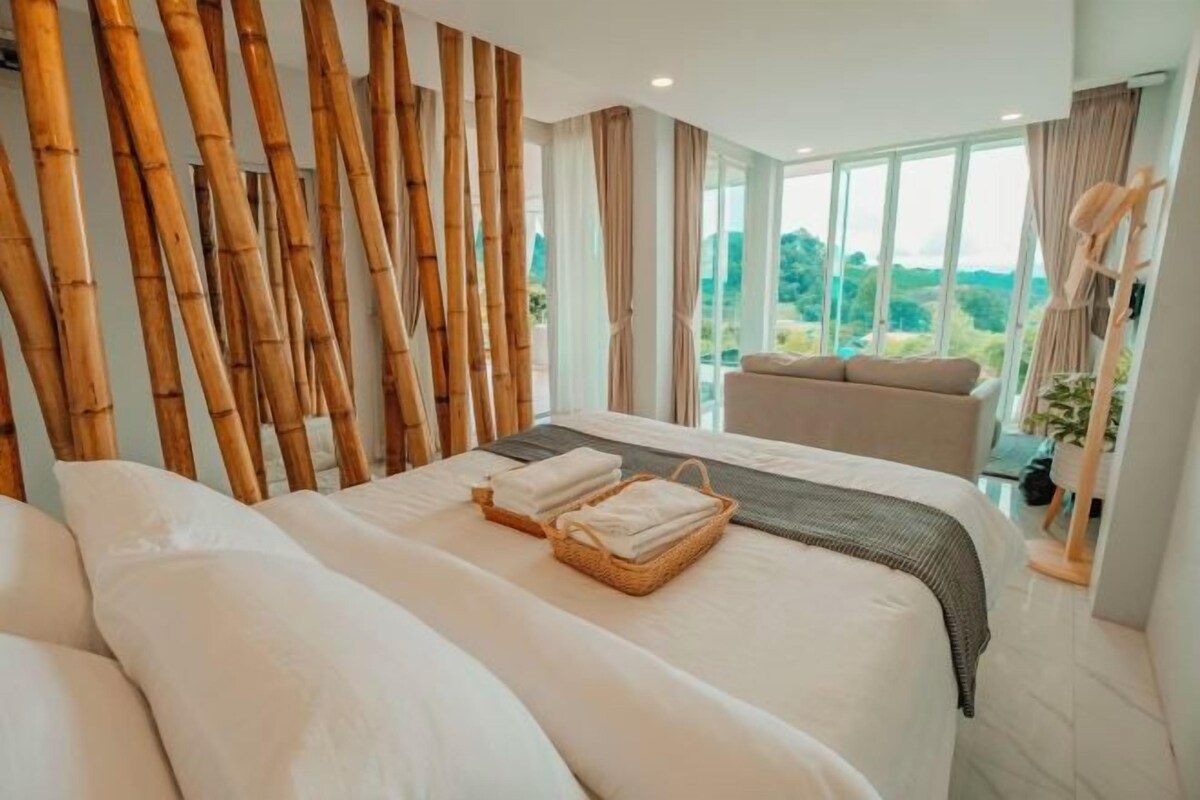 A modern hotel room with a large bed, a seating area, and a view of the outdoors.